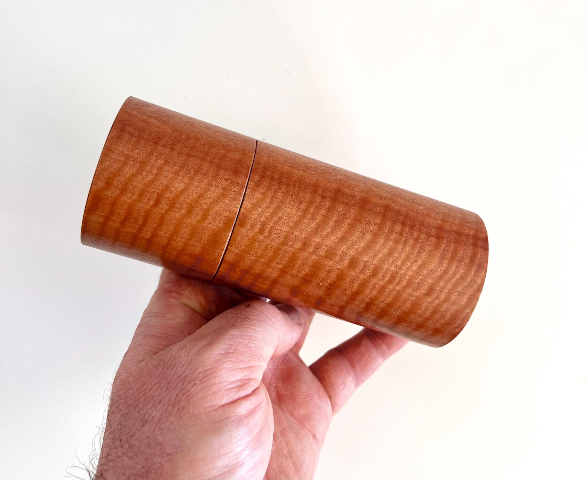 Mans hand holding single straight cylindrical Wandoo timber grinder