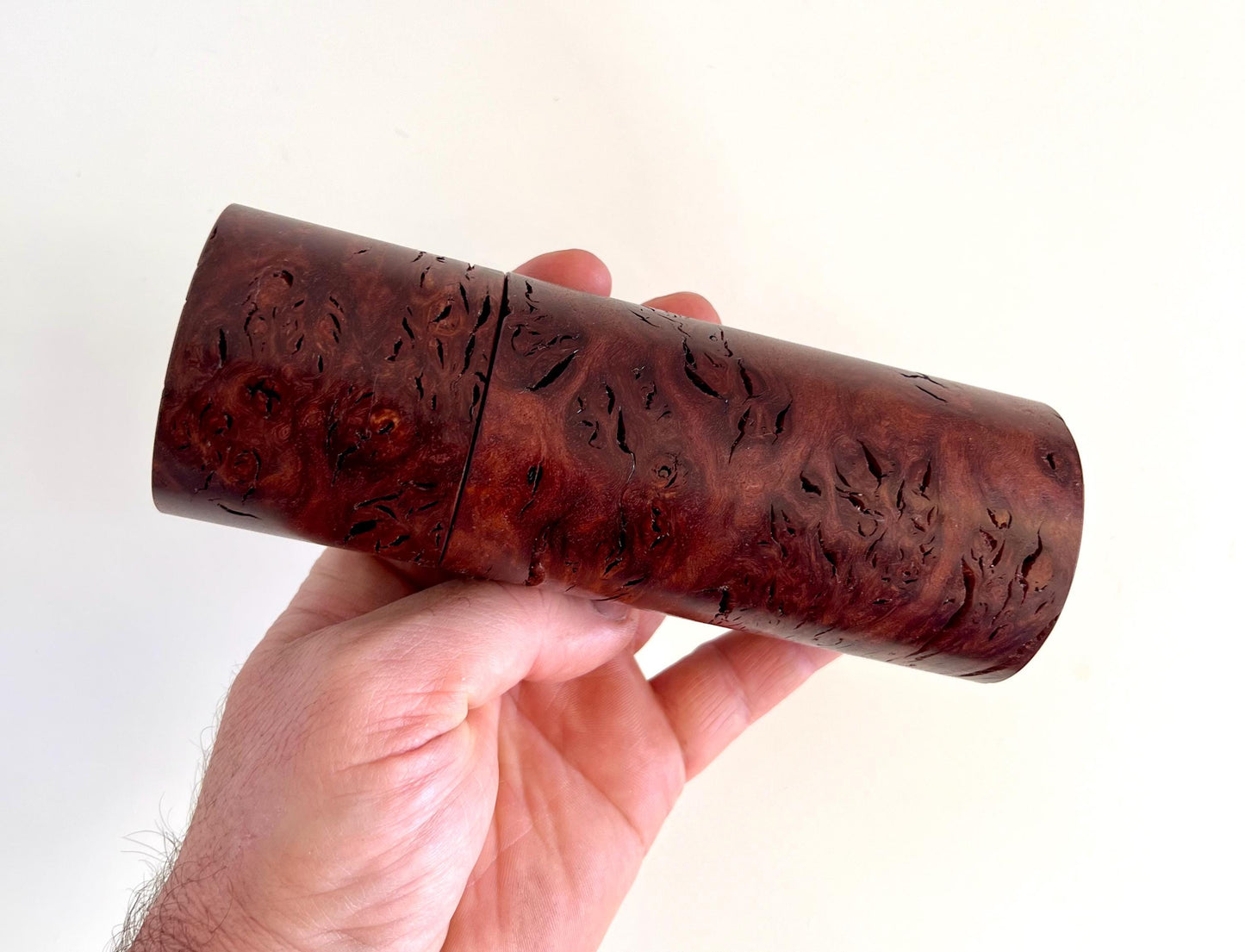 Mans hand holding single straight cylindrical Jarrah burl timber grinder