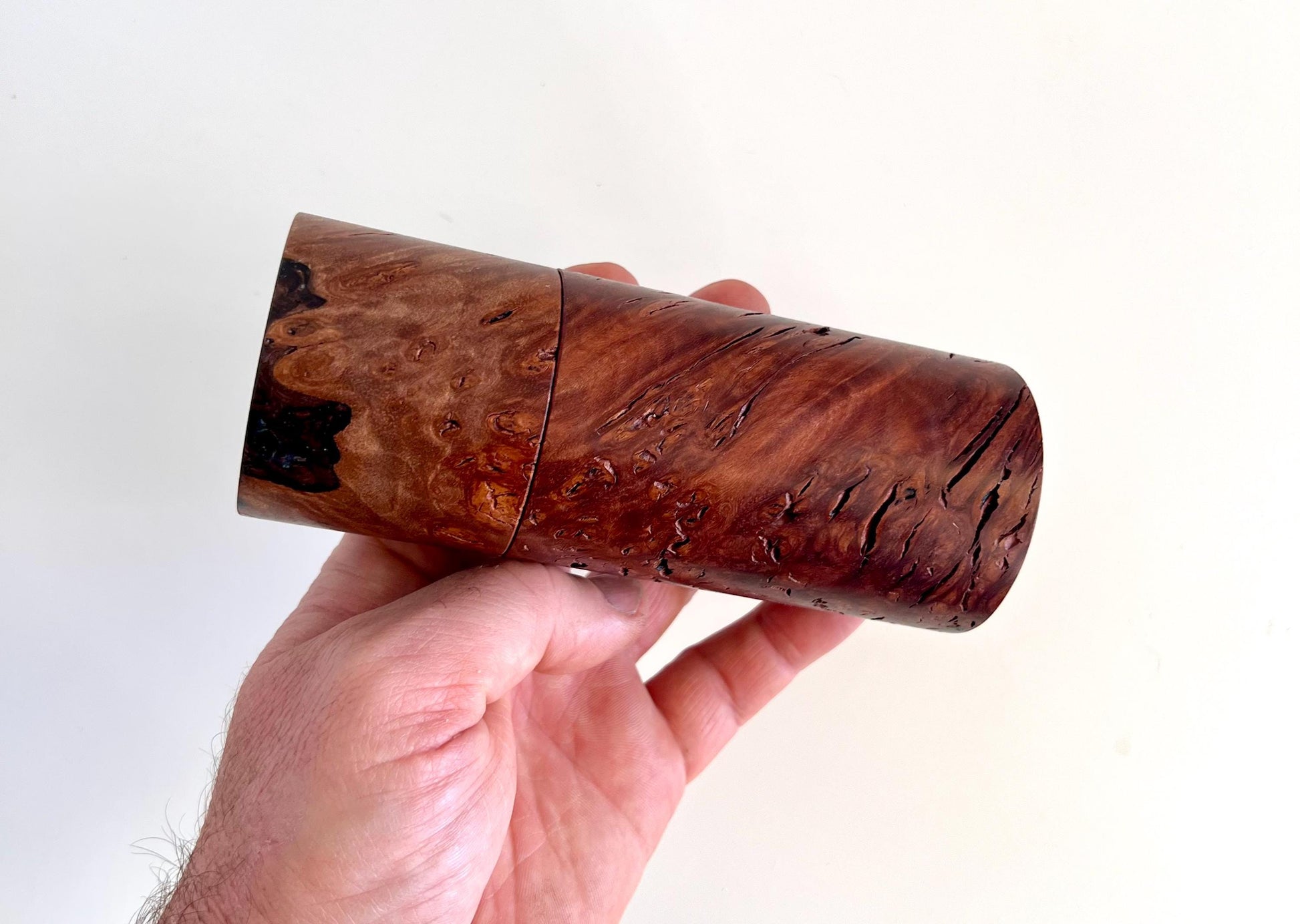 Mans hand holding single straight cylindrical Jarrah burl timber grinder