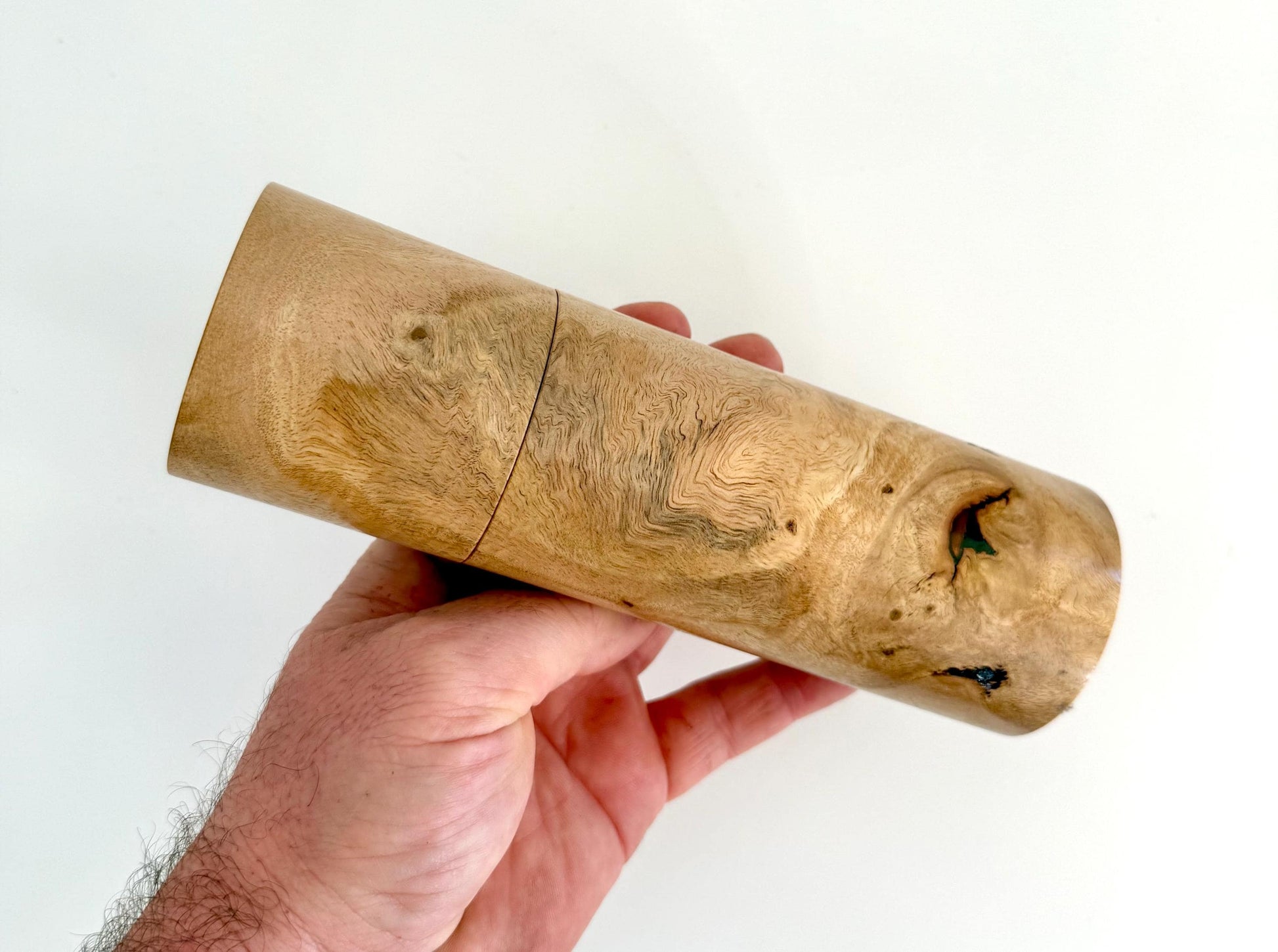 Mans hand holding single straight cylindrical Lemon scented gum timber grinder
