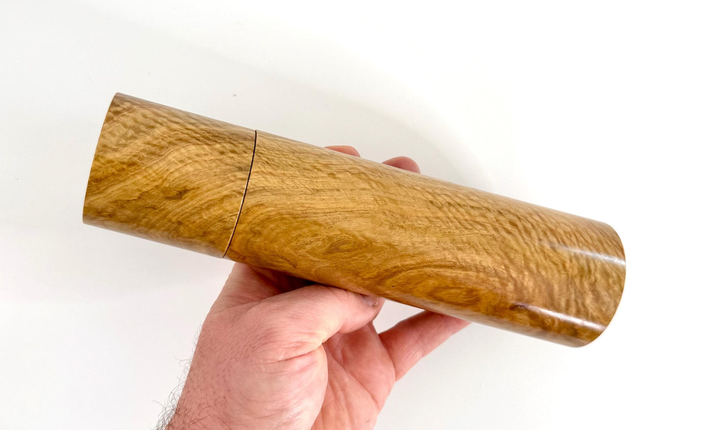 Mans hand holding single straight cylindrical Bimble Box Burl timber grinder