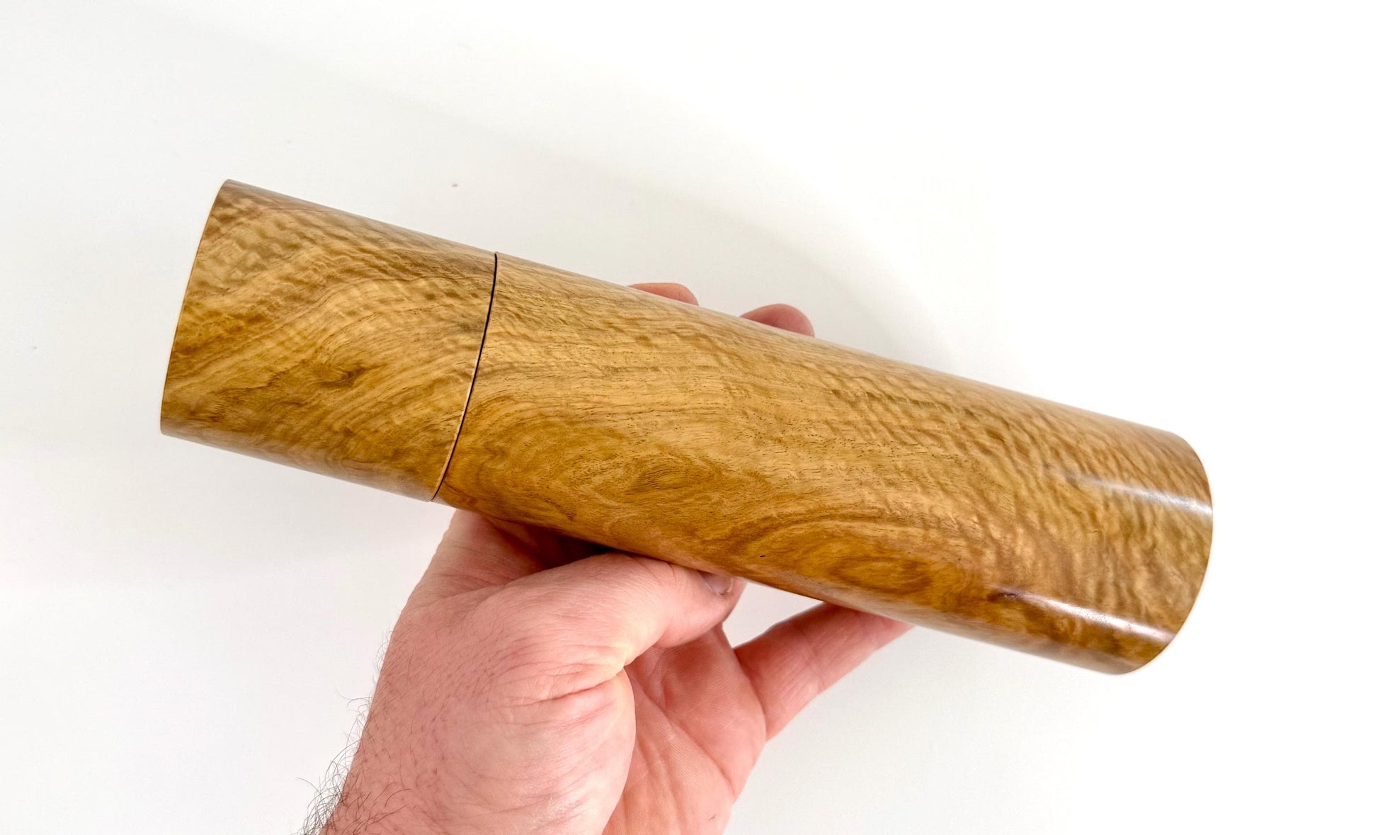 Mans hand holding single straight cylindrical Bimble Box Burl timber grinder