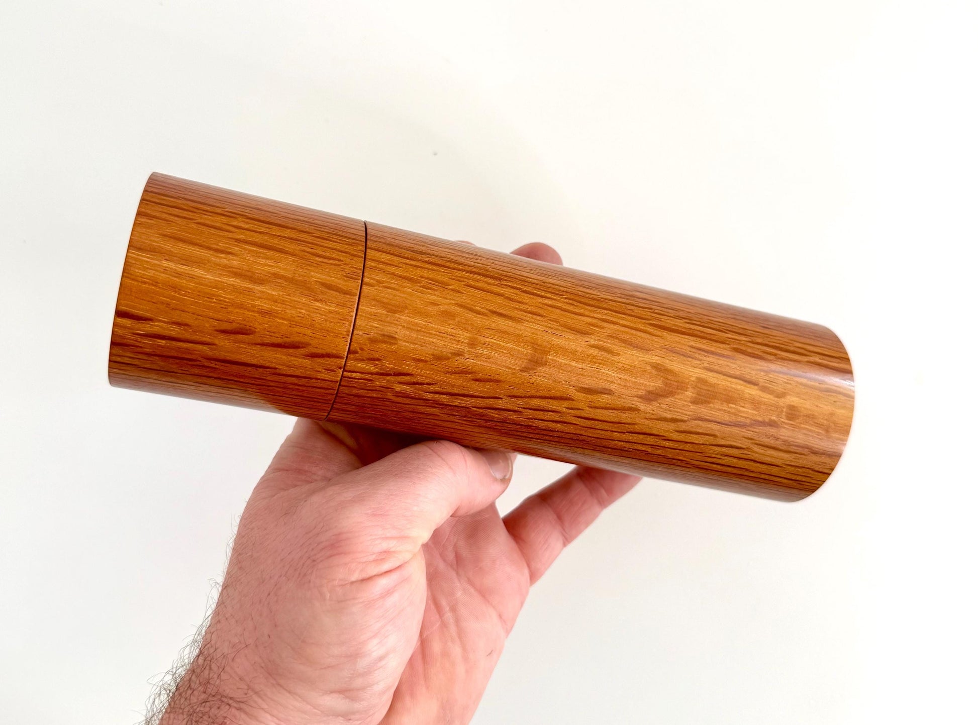 Mans hand holding single straight cylindrical Sheoak timber grinder