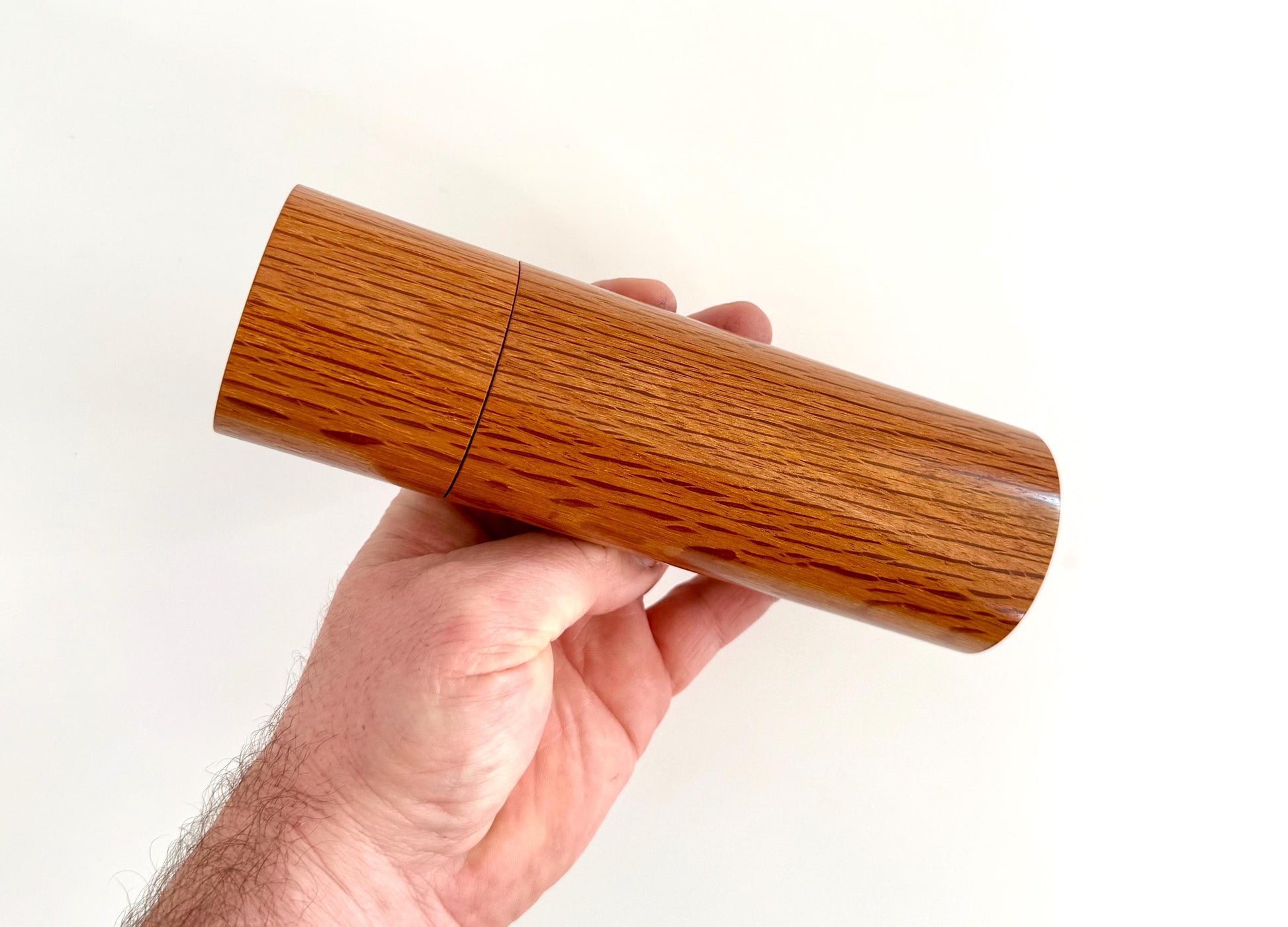 Mans hand holding single straight cylindrical Sheoak timber grinder