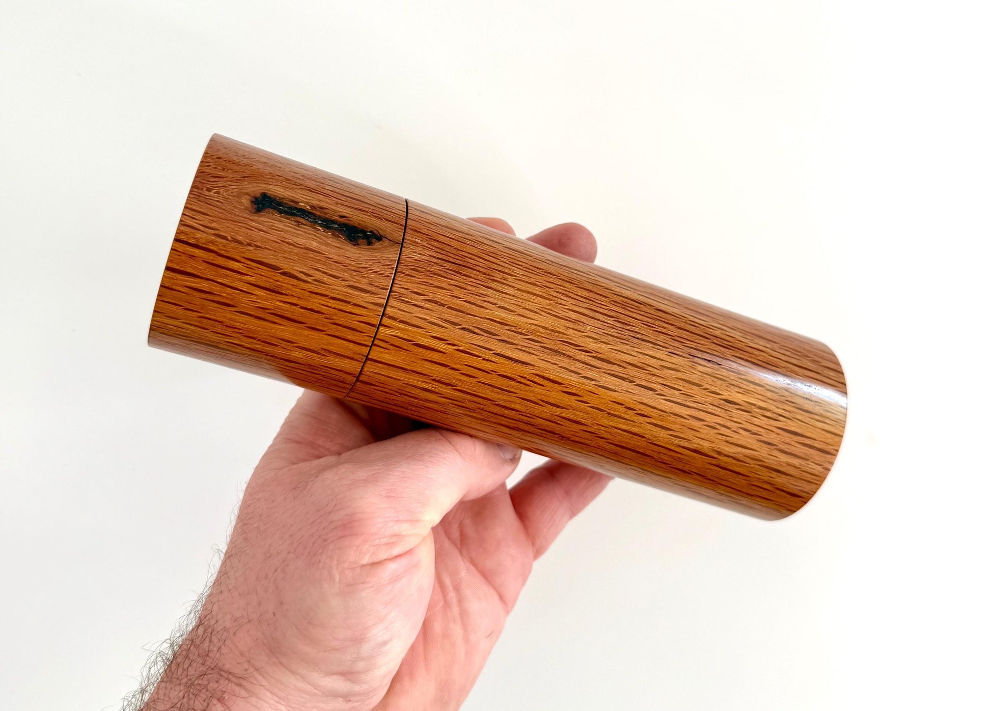 Mans hand holding single straight cylindrical Sheoak timber grinder
