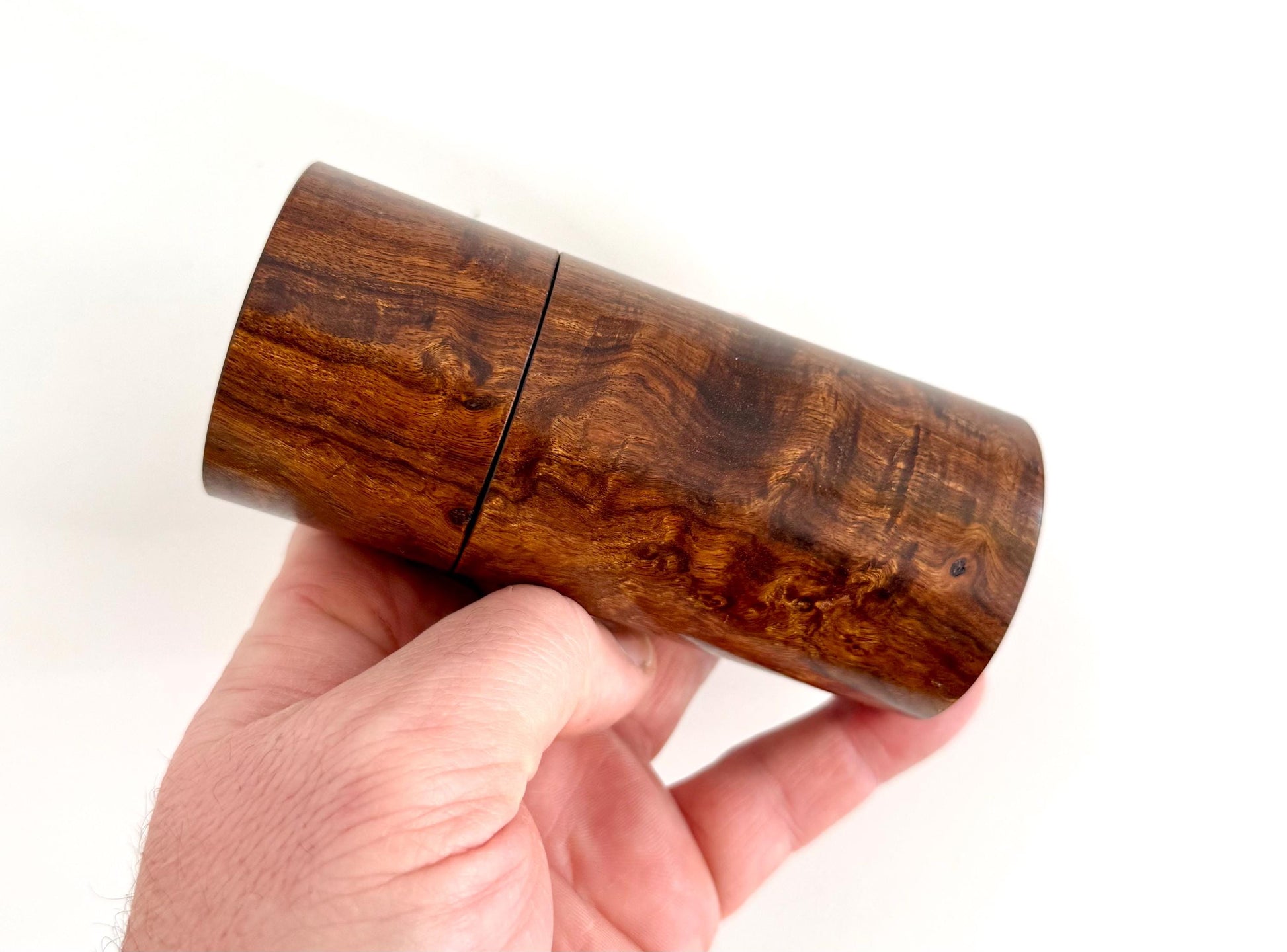 Mans hand holding single straight cylindrical Black Mulga timber grinder