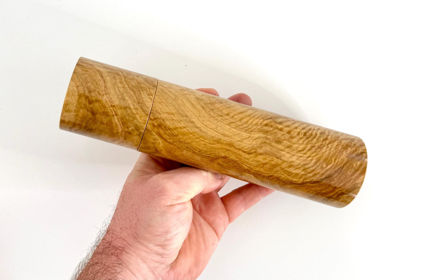 Mans hand holding single straight cylindrical Bimble Box Burl timber grinder