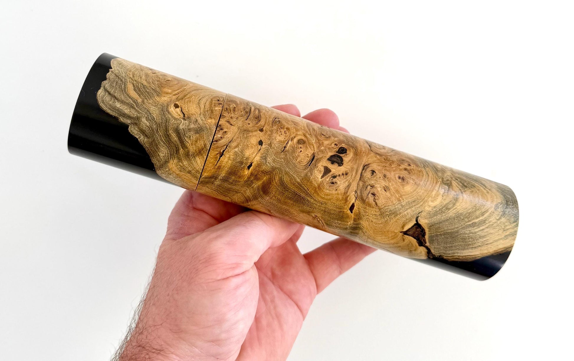 Mans hand holding single straight cylindrical Marri timber grinder