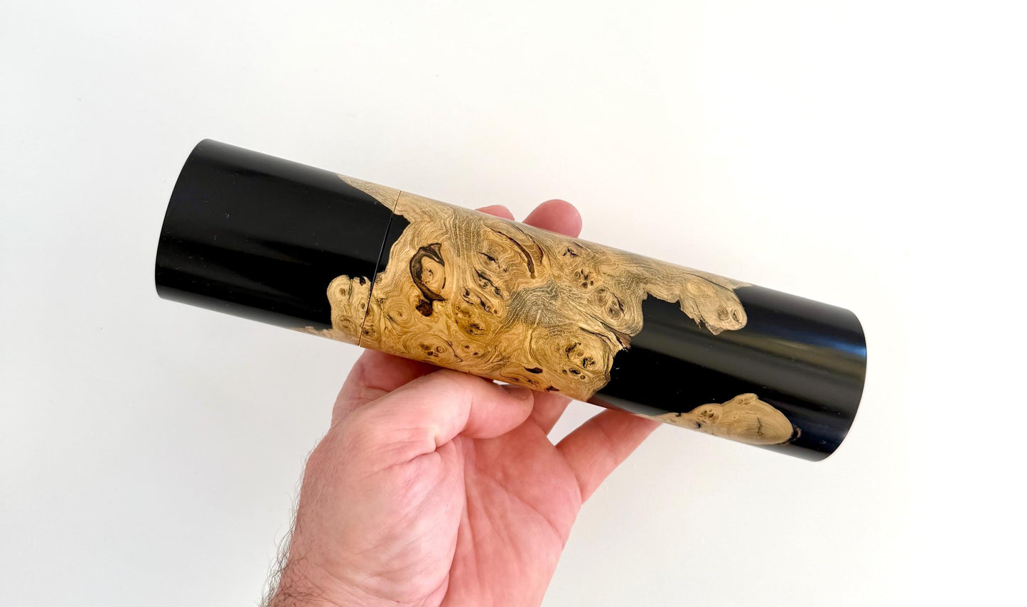 Mans hand holding single straight cylindrical Marri timber grinder