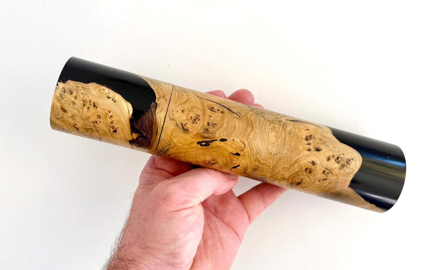 Mans hand holding single straight cylindrical Marri timber grinder
